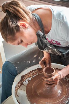 Beautiful woman making ceramic pottery on wheel, hands close-up. Concept for woman in freelance, business, hobby