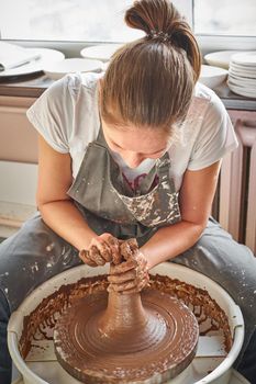 Beautiful woman making ceramic pottery on wheel, hands close-up. Concept for woman in freelance, business, hobby