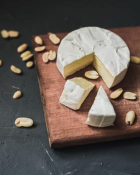 cheese camembert with mold and nuts on the wooden cutting board