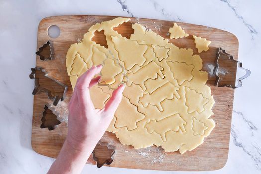 the process of cutting figures from shortcrust pastry for cookies with forms in the form of Christmas trees and animals