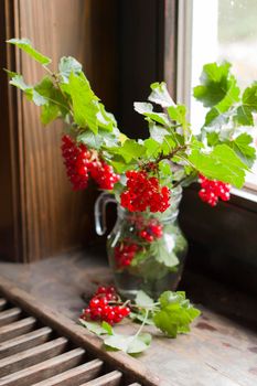 Fruit still life with a bouquet of red currant branches and tea in a transparent glass, natural food, vegetarian tea, summer berry picking