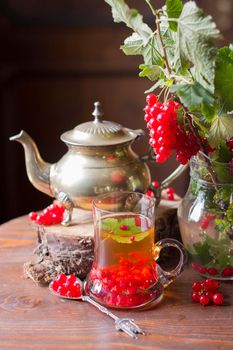 Fruit still life with a bouquet of red currant branches and tea in a transparent glass, natural food, vegetarian tea, summer berry picking