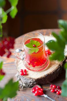 Fruit still life with a bouquet of red currant branches and tea in a transparent glass, natural food, vegetarian tea, summer berry picking