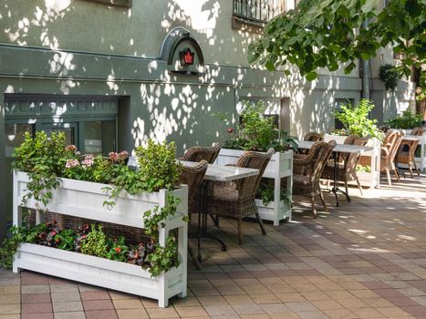 KRASNODAR, RUSSIA - June 02, 2021. Street cafe with flower beds and wicker furniture.