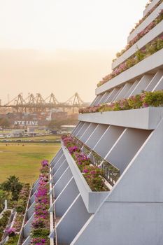 SINGAPORE, SINGAPORE - January 17, 2013. Balconies with decorative flowers of Marina Bay Sands and cargo cranes of sea port.