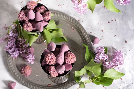Belgian sweets cuberdon and pralines in silver glasses, spring still life,lilac . High quality photo