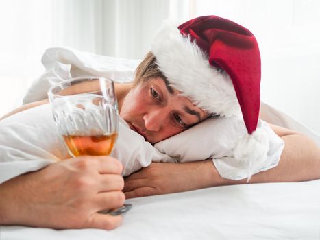 Man in Santa hat is trying to freshen the nip after alco party. He is suffering of headache after New Year or Christmas celebration. Heavy morning. Alcohol withdrawal. Worst hangover.