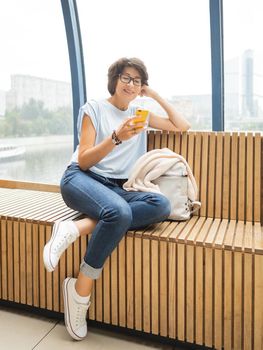 Smiling woman in eyeglasses texting on smartphone. Millennials lifestyle. Casual clothes.