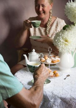 tea break in the English style, still life with flowers and donuts in the morning sun, homemade cakes, married couple drinking tea together at breakfast in english style, beautifully set table