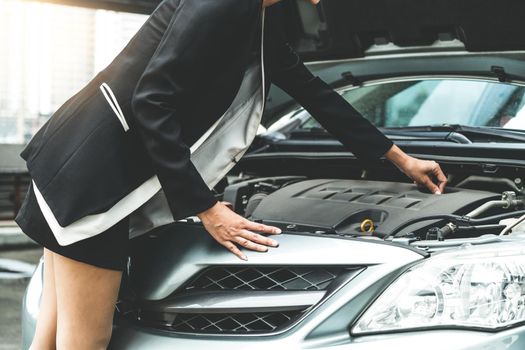 A business woman whose car breakdown try to fix the car by herself without help.