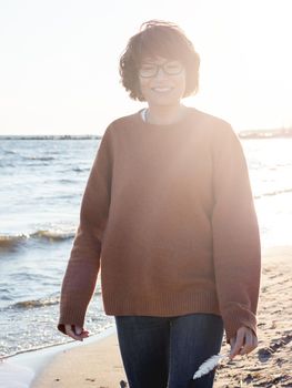 Portrait of smiling woman on seaside. Woman with hair ruffled with the wind. Walking at sunset by the sea.