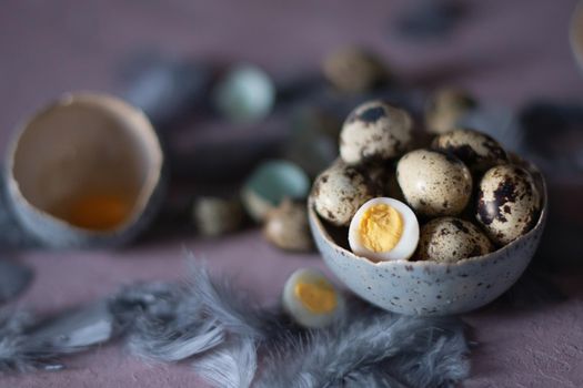 quail eggs in ceramic vases, gray feathers on the table, easter still life, natural food, diet and antioxidants, dark key and shallow depth of field. High quality photo