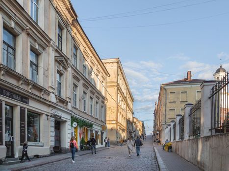 VYBORG, RUSSIA - August 16, 2021. Tourists walk on Krepostnaya street. Cobblestoned street with old fashioned shops and cafe.