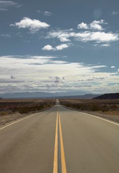 Long and straight road to the horizon under a cloudy sky