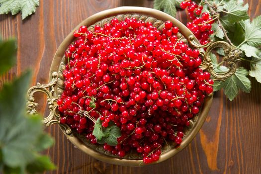 Fresh red currant in the rustic metal plate on a wooden table. High quality photo