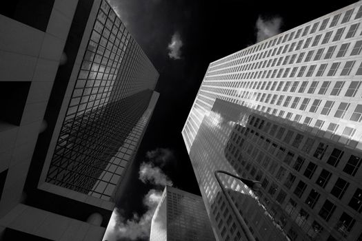 A couple of skyscrapers view from below with a dark sky in black and white in Los Angeles