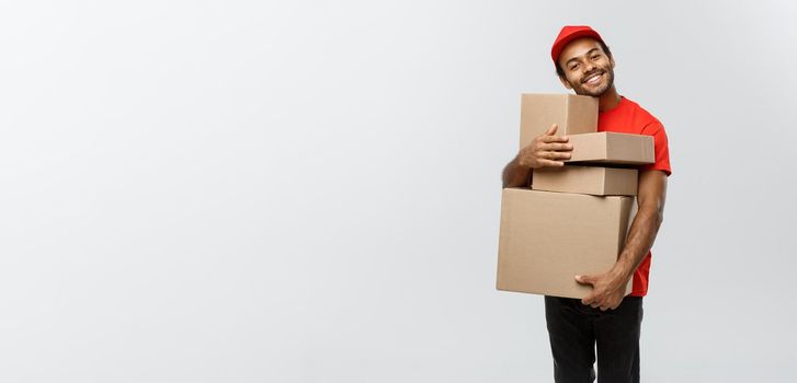 Delivery Concept - Portrait of Happy African American delivery man in red cloth holding a box package. Isolated on Grey studio Background. Copy Space