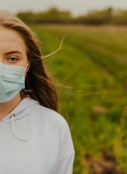 Young blond European woman in a protective mask outdoors.