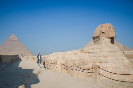 A European blonde walks near the pyramids in the desert in Cairo. The girl against the background of ancient buildings in Giza. Egyptian Sphinx