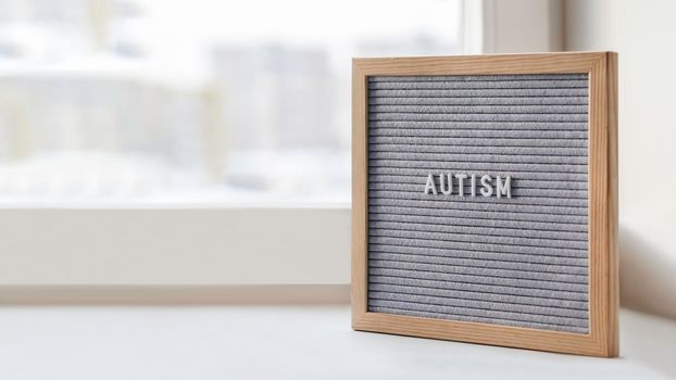 Grey letterboard with word Autism. Medical diagnosis which usually made in childhood. Drawing attention to development of children. Copy space.