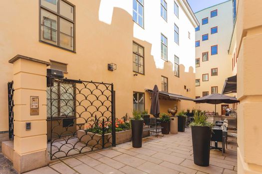 STOCKHOLM, SWEDEN - July 06, 2017. Cafe with open doors and tables outdoors. Sun reflections on beige walls of Gamla stan. Colorful old fashioned buildings in historical part of town.