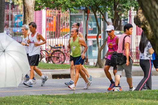 BANGKOK, THAILAND - October 23, 2012. Sporty men are jogging in urban park Lumpini. Healthy lifestyle in Asian town.