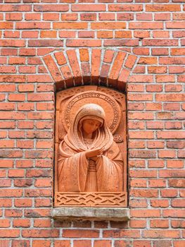 SVETLOGORSK, RUSSIA - July 21, 2019. Statue of Madonna in red brick wall near entrance of orthodox Church of Seraphim of Sarov in old building of lutheran kirk.