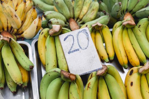 Green and yellow bananas on stall at marketplace. Traditional local fruits on street market. Bangkok, Thailand.