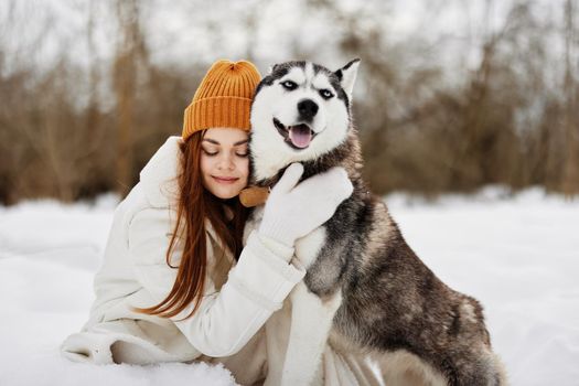 young woman in the snow playing with a dog fun friendship Lifestyle. High quality photo