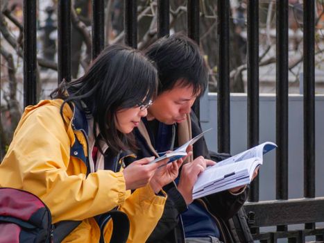 MOSCOW, RUSSIA - April 18, 2007. Couple of Asian tourists read aloud touristic guide at street. Wanderlust people at journey.