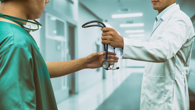 Doctor passing stethoscope to surgeon. Concept of specialist referral patients from general practitioner GP for further medication.