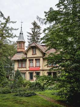 SVETLOGORSK, RUSSIA - July 21, 2019. Old building with dense garden. Red advertisement - sale of this real estate.