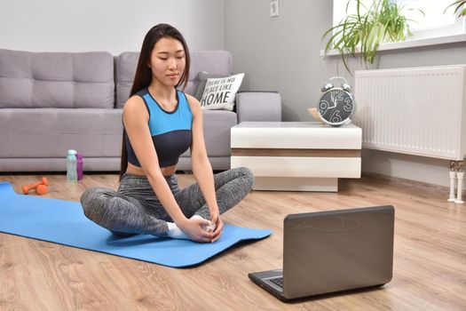 Young asian woman making yoga at home. Carantin and hobby. Home isolation. Online training. Soft focus