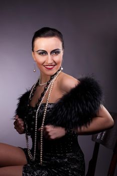 Proud woman smile in fur boa with pearl beads on chair