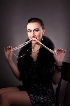 Beauty woman with vintage make-up take pearls in teeth