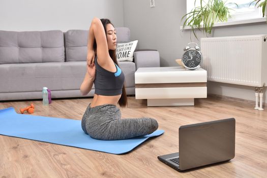 Young asian woman making yoga at home. Carantin and hobby. Home isolation. Online training. Soft focus