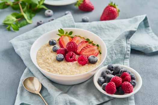 Oatmeal with blueberry, strawberry, raspberry on blue dark background. Side view. Healthy diet breakfast