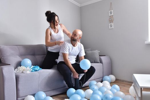 Family couple blowing white and blue balloons. Man and woman preparing before party