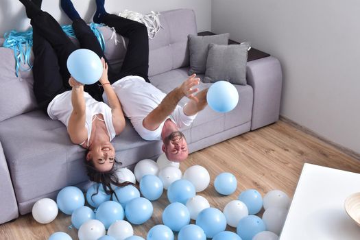 Family couple blowing white and blue balloons. Man and woman preparing before party