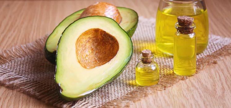 Avocado and avocado oil on wooden background. Selective focus.food