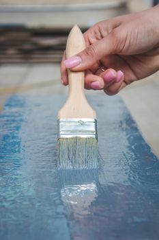 girl paints a board with a brush. Paint with gray paint. selective focus