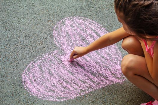 child painted a heart on the asphalt with chalk. selective focus.art