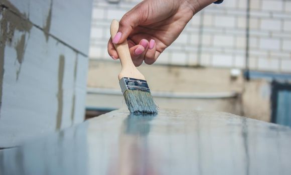 girl paints a board with a brush. Paint with gray paint. selective focus