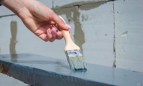 girl paints a board with a brush. Paint with gray paint. selective focus