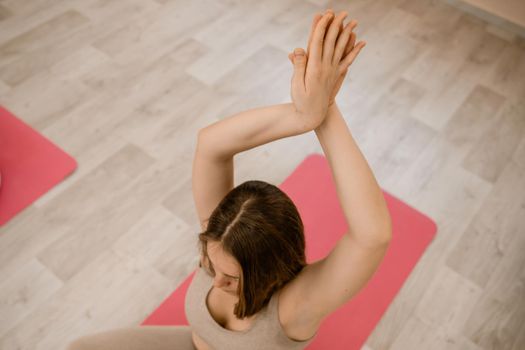 Girl does yoga. Young woman practices asanas on a beige one-ton background