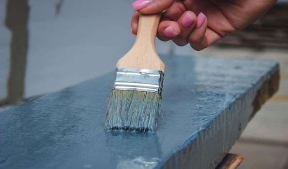 girl paints a board with a brush. Paint with gray paint. selective focus