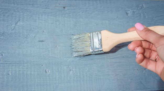 girl paints a board with a brush. Paint with gray paint. selective focus