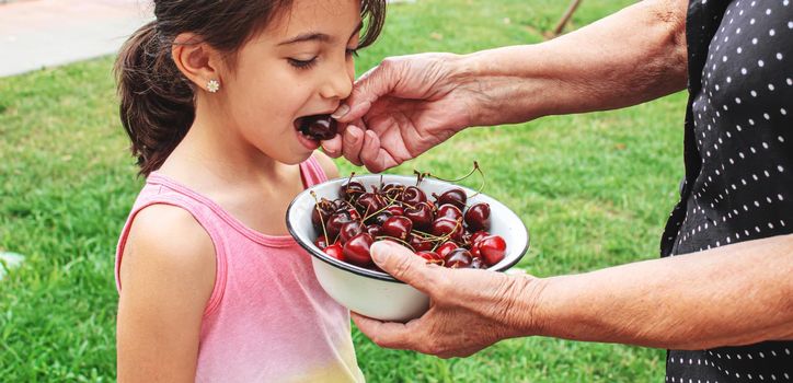 grandparents feed the child with cherries.selective focus.nature