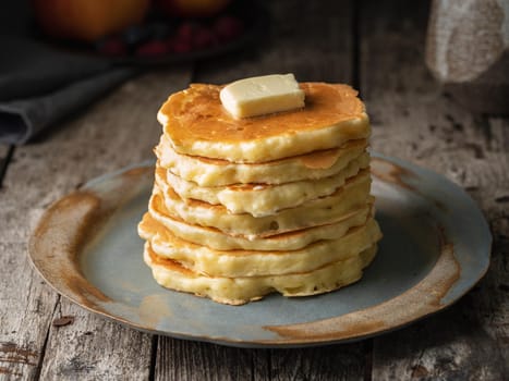 Pancake with butter, close-up. Dark moody old rustic wooden background.