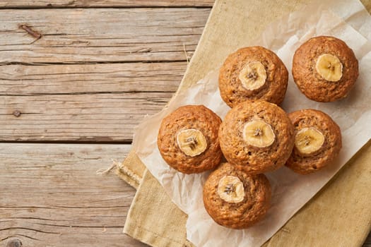 Banana muffin, top view, copy space. Cupcakes on old linen napkin, rustic wooden table, breakfast with cake